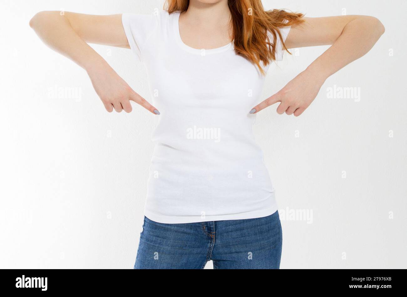 T-shirt design and advertising concept. Style and fashion. Indoor shot of cheerful smiling youngred head woman with red hair pointing index finger at Stock Photo