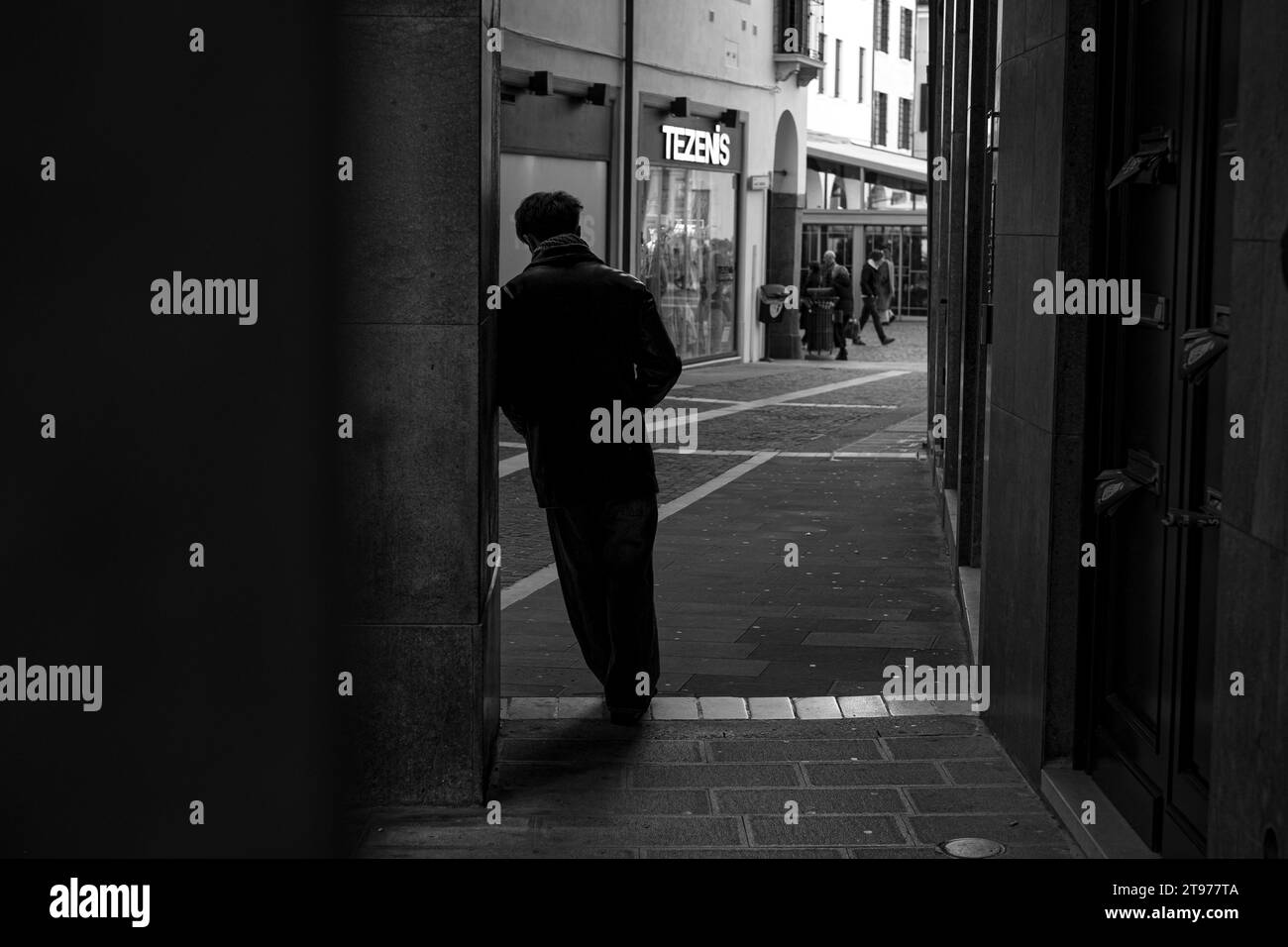 Person leaning with his shoulder against the wall against the light. Black and white photos. Stock Photo