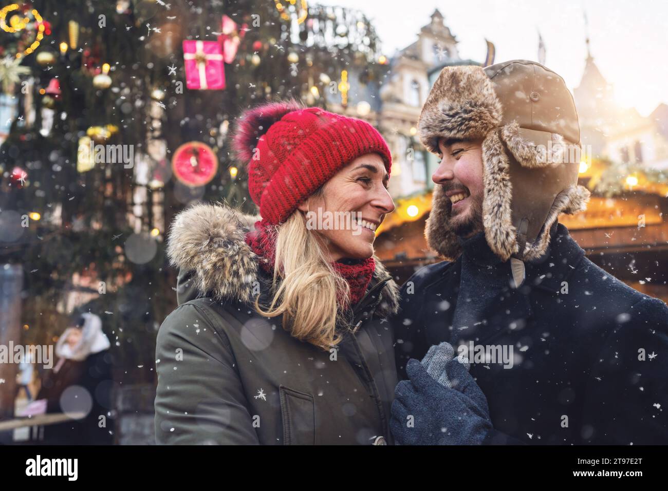 Couple in love smiling affectionately at each other in a snowy Christmas market Stock Photo