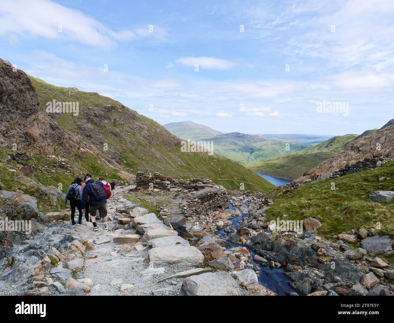 Rear view of group of hikers with backpacks walking down the Miners' Track from Mount Snowdon in stunning scenery of Snowdonia mountains in Wales, UK. Stock Photo