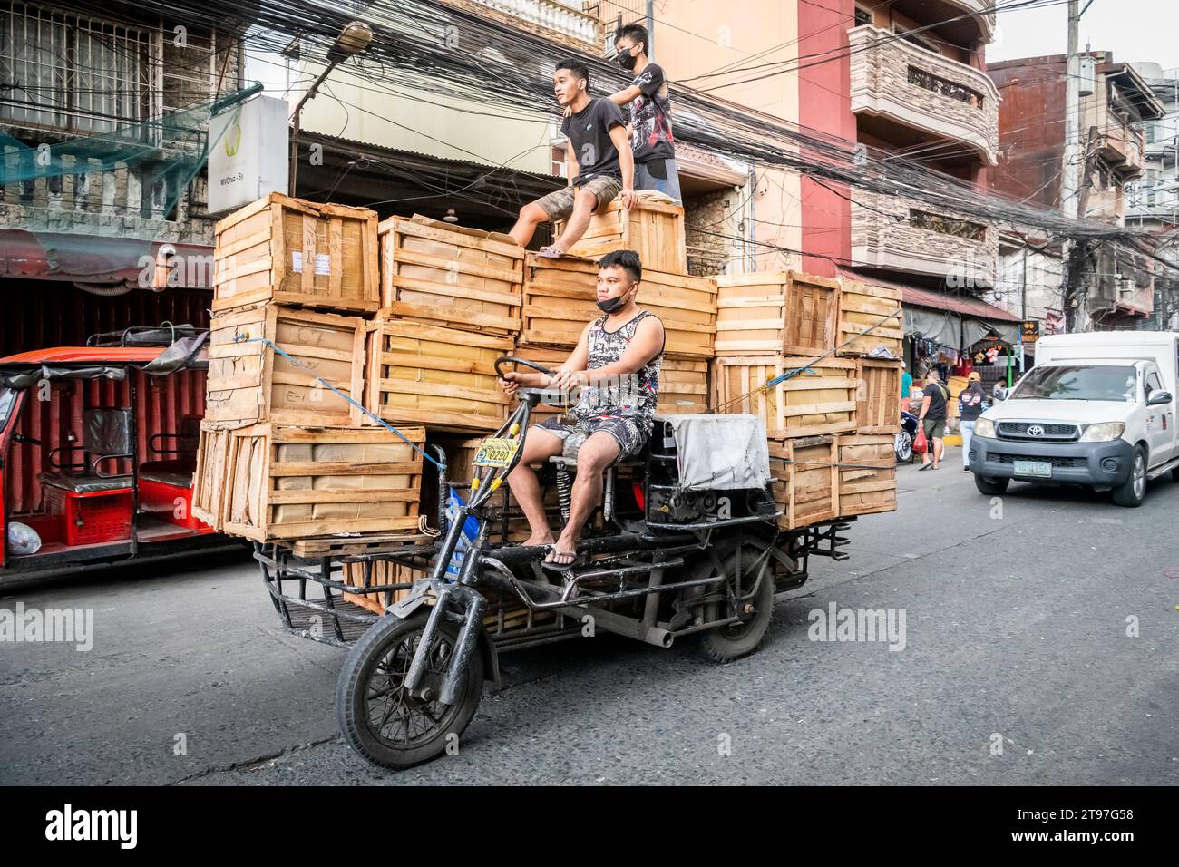 Some Filipino workers deliver wooden crates on a tractor style vehicle