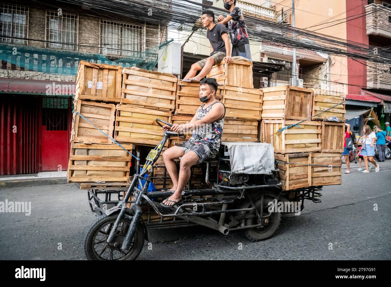 Some Filipino workers deliver wooden crates on a tractor style vehicle