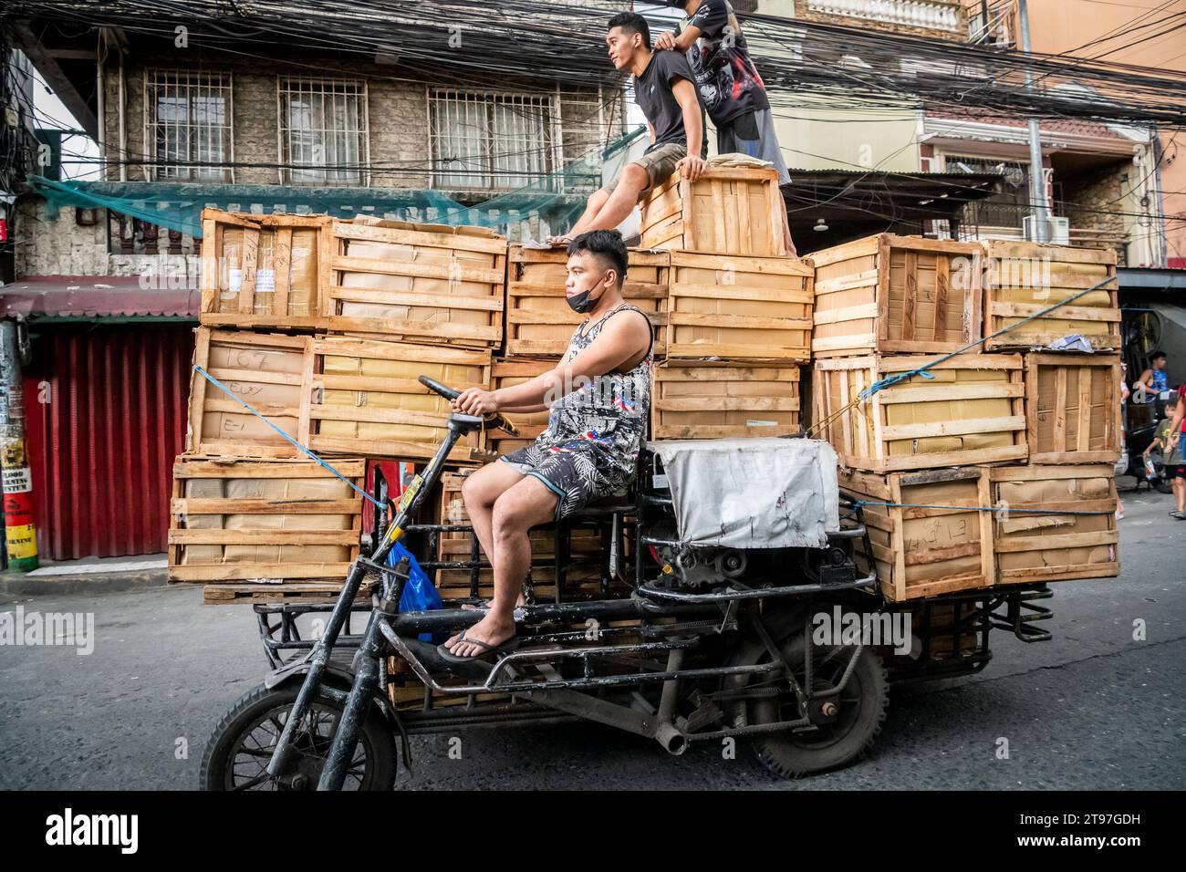 Some Filipino workers deliver wooden crates on a tractor style vehicle