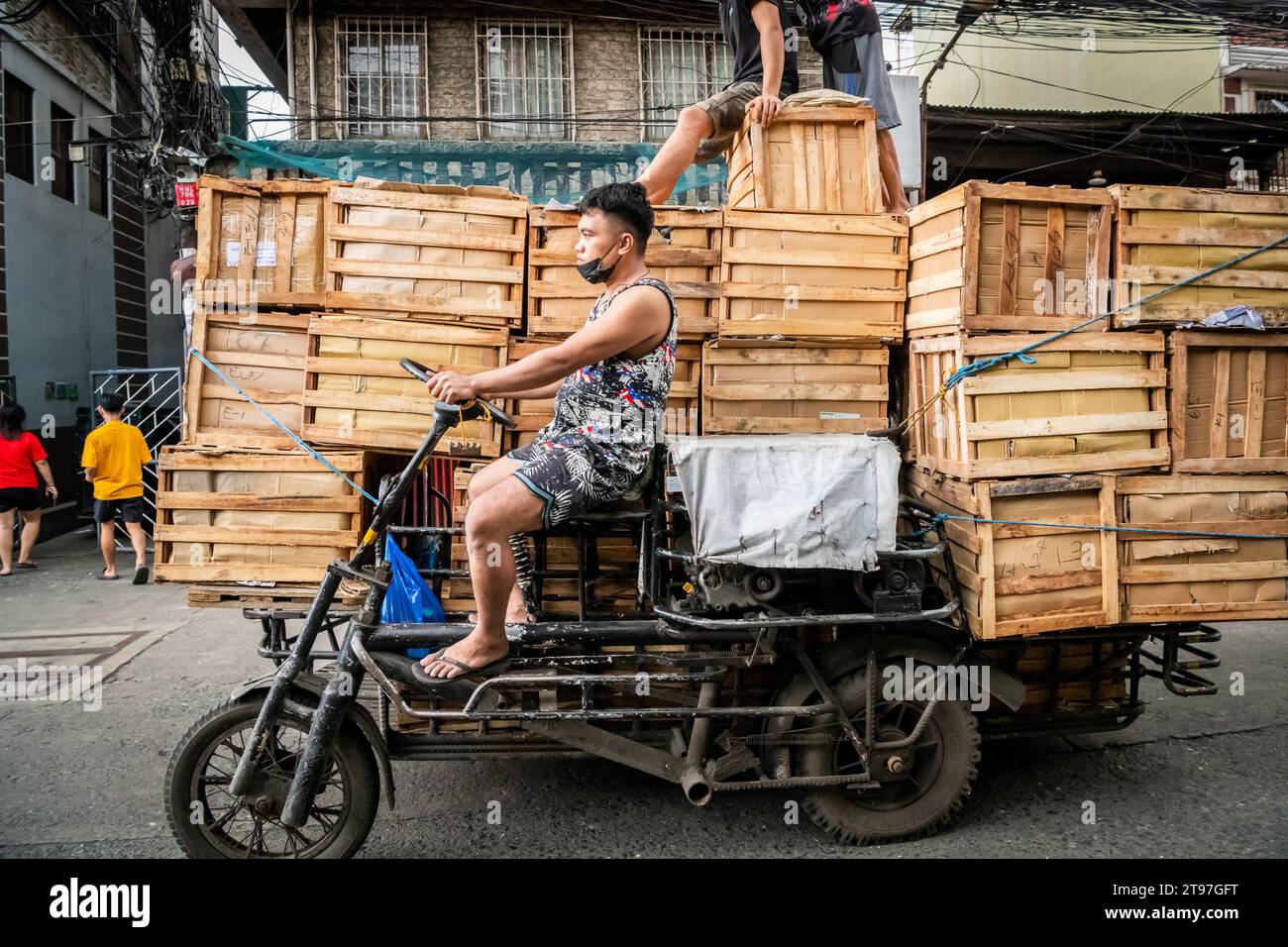 Some Filipino workers deliver wooden crates on a tractor style vehicle