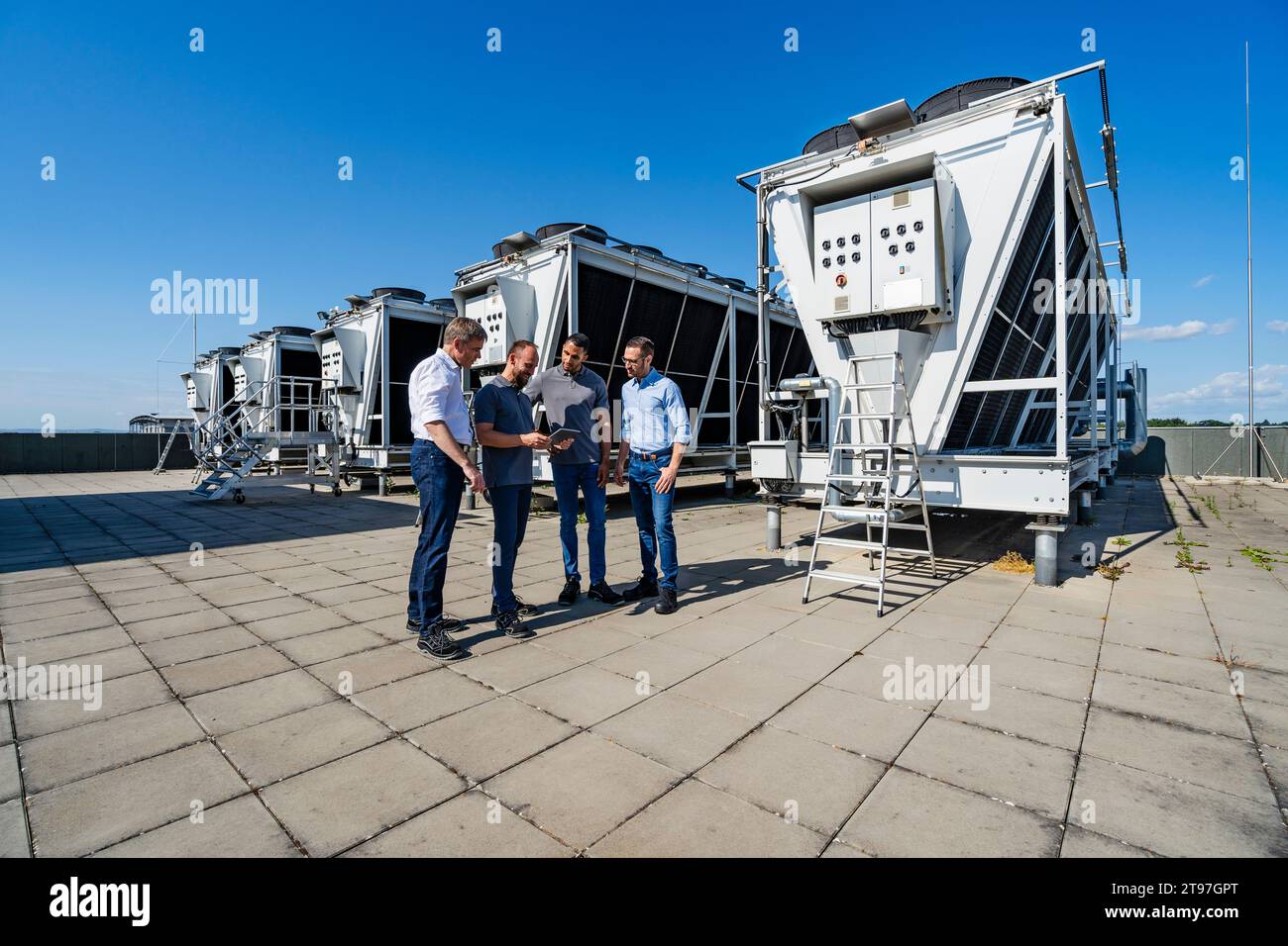 Businessmen and employees having a meeting on rooftop beside refrigeration installation Stock Photo