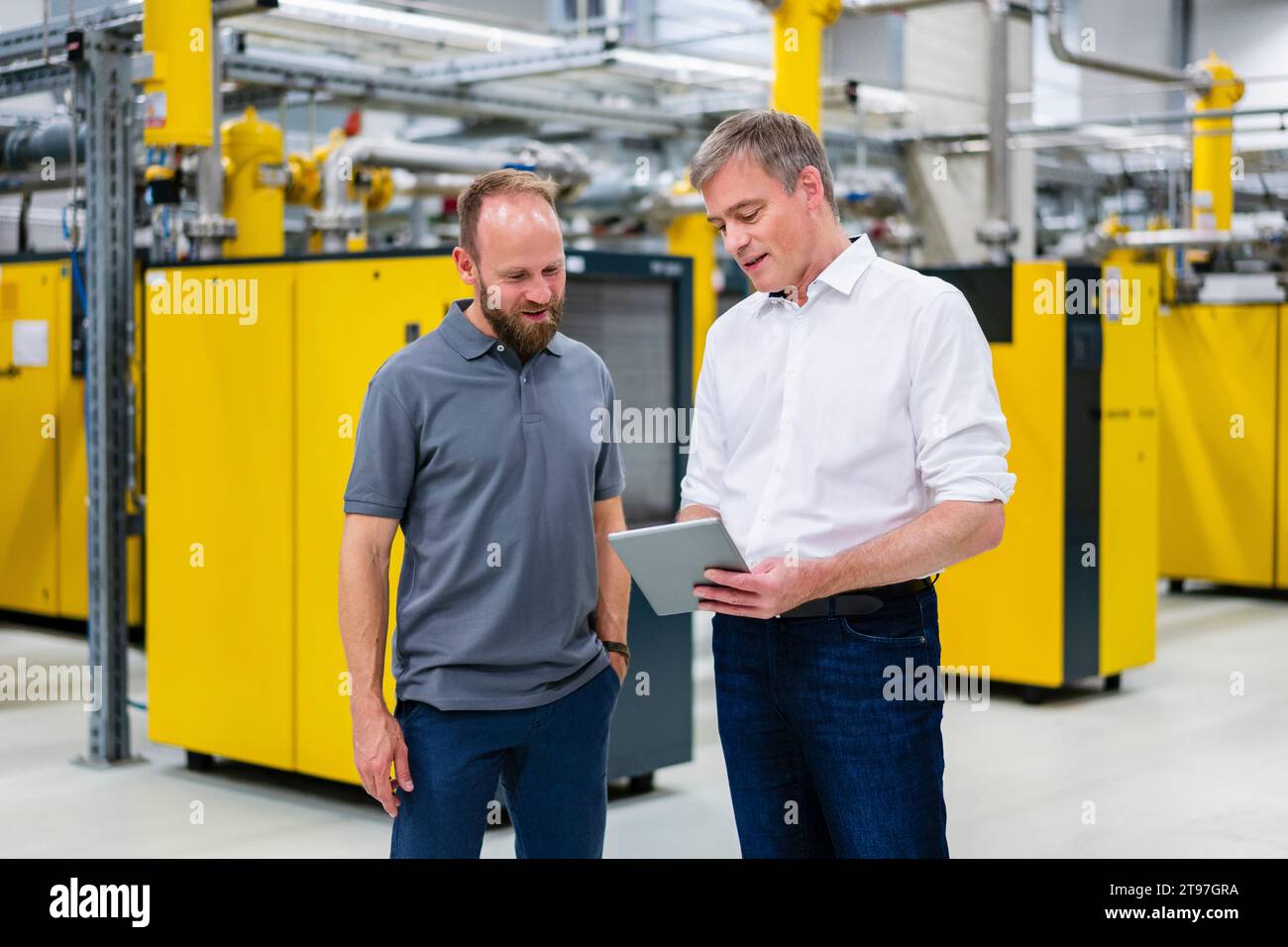 Employee and businessman with digital tablet talking in factory Stock Photo
