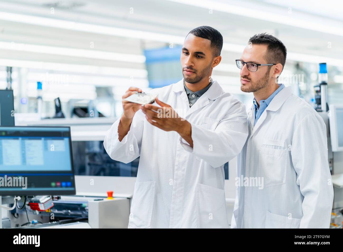 Electrotechnicians checking motherboard in electronics factory Stock Photo