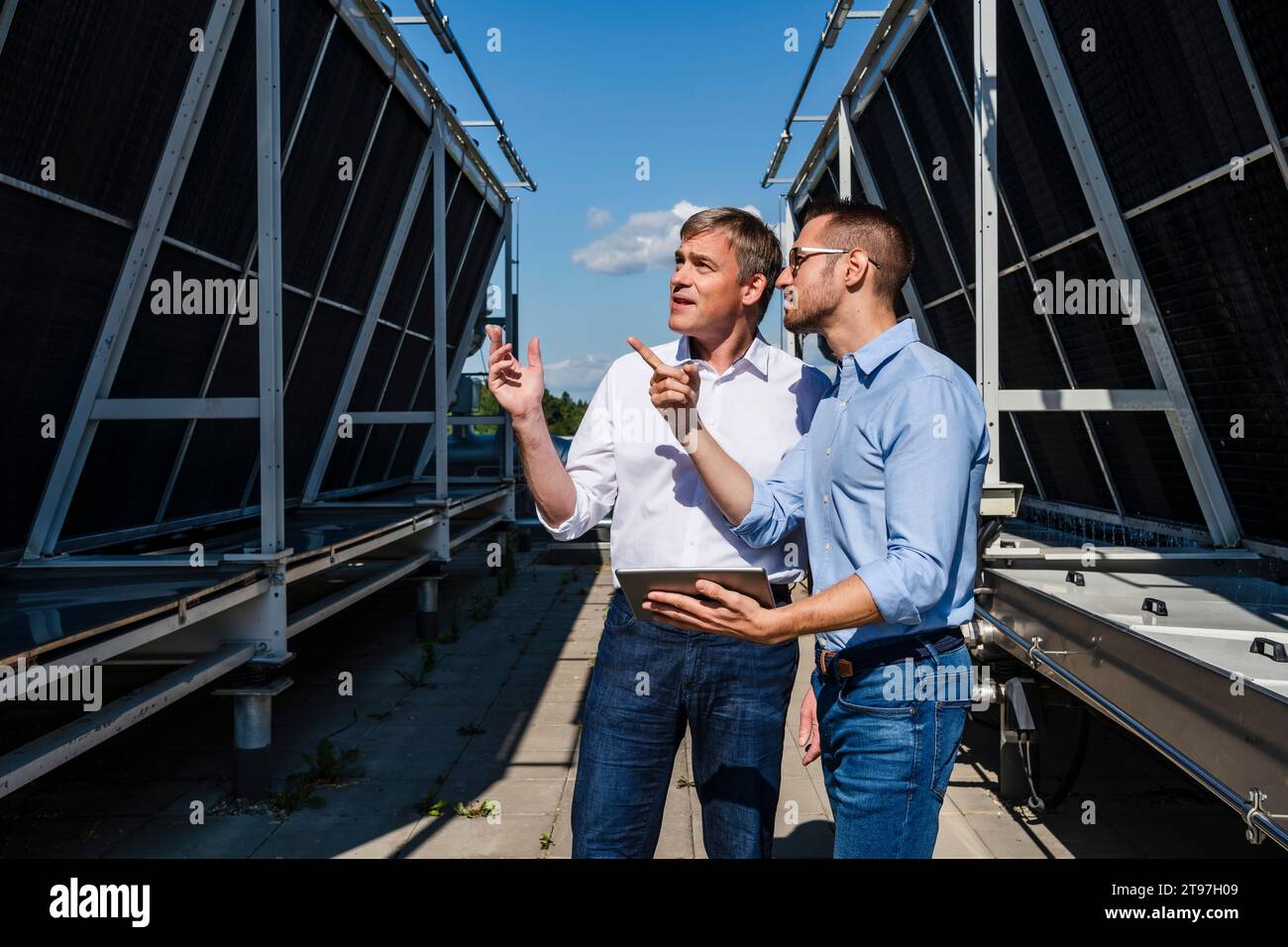 Two businessmen discussing on rooftop beside refrigeration installation Stock Photo