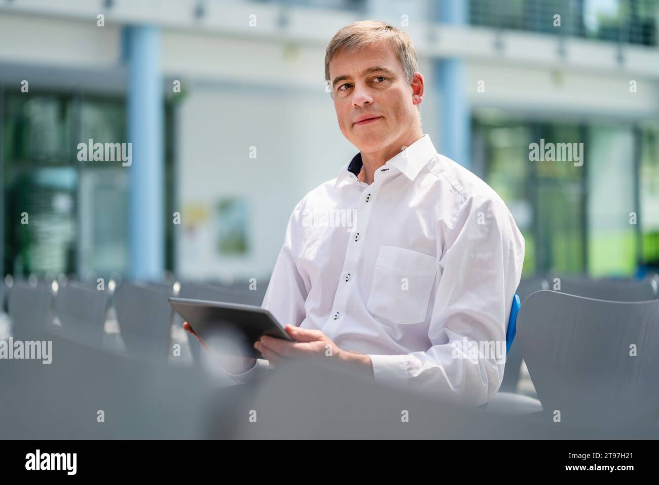 Businessman sitting in company auditory using digital tablet Stock Photo