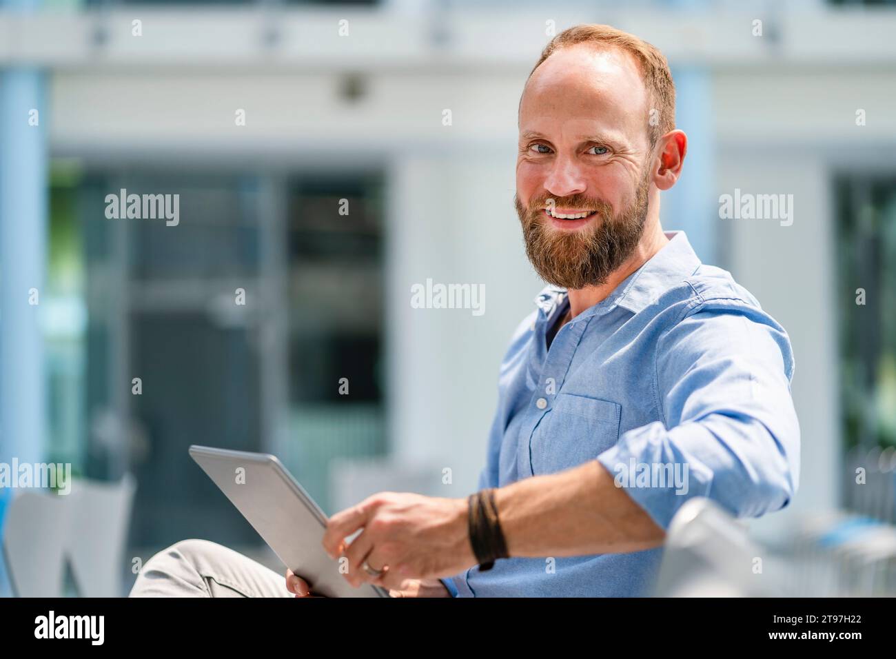 Businessman sitting in company auditory using digital tablet Stock Photo