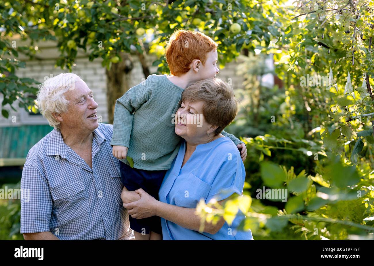 Senior man and woman with grandson in garden Stock Photo