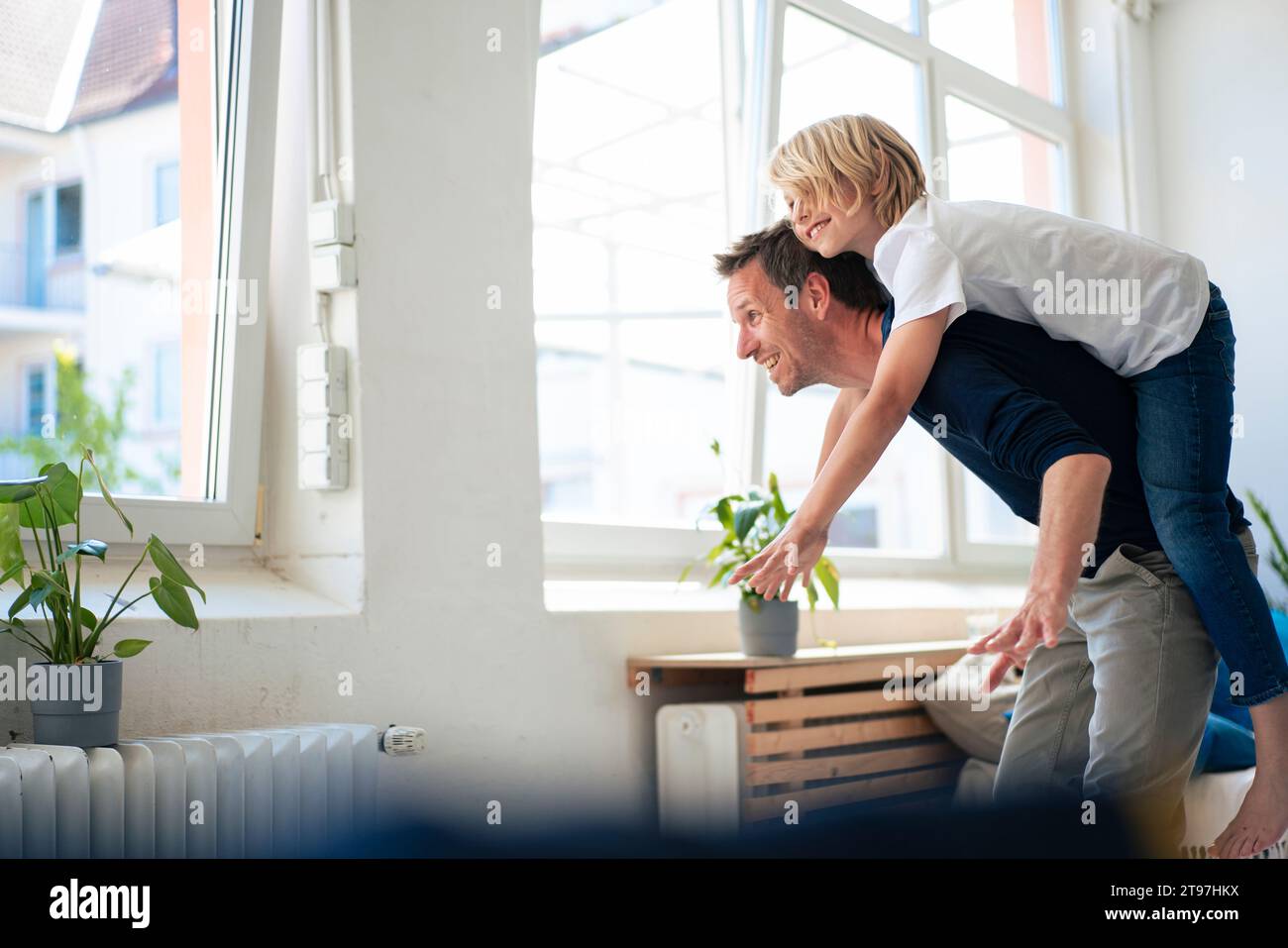 Happy father giving piggyback ride to son at home Stock Photo