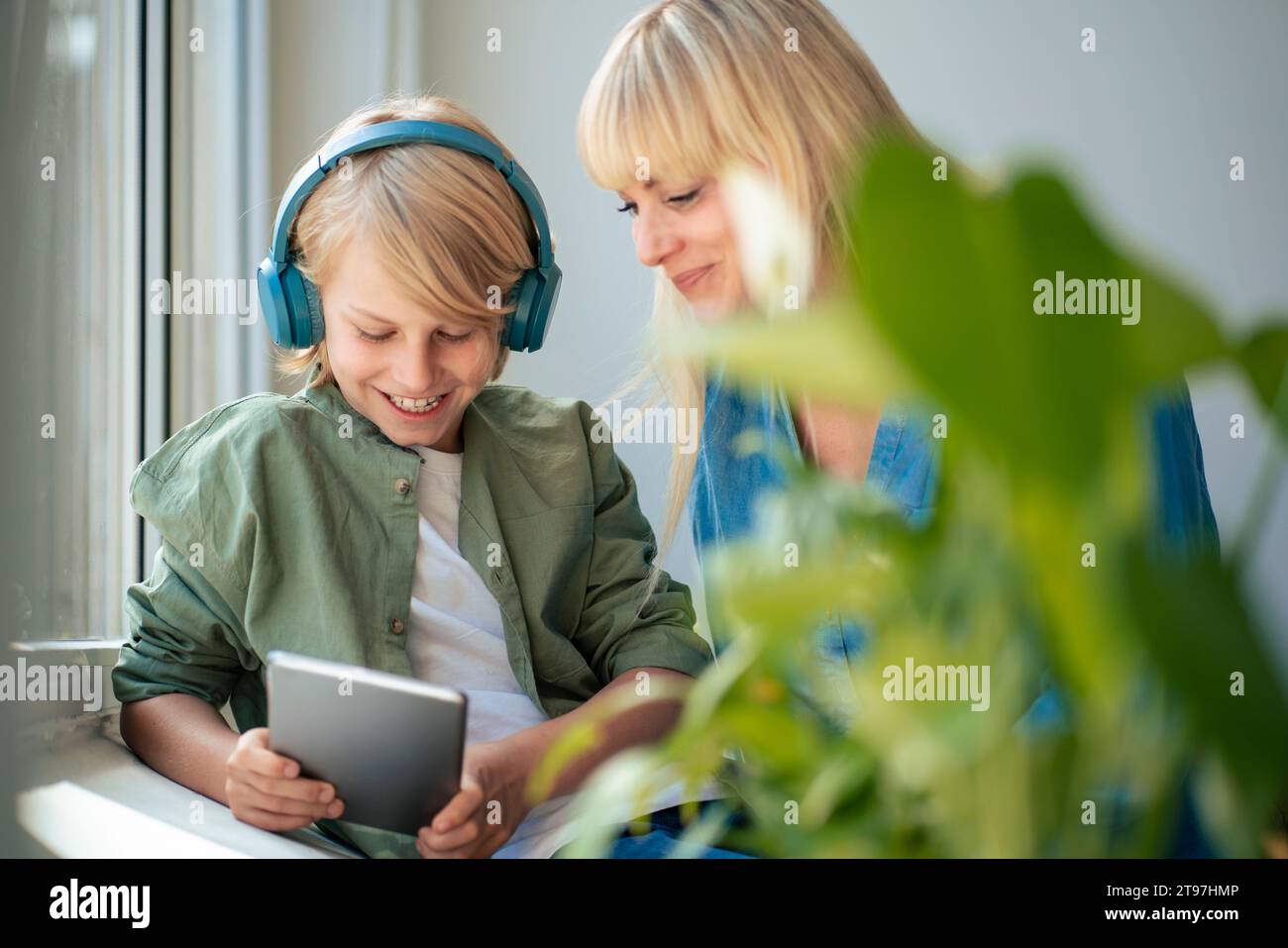 Smiling mother with son using tablet PC at home Stock Photo