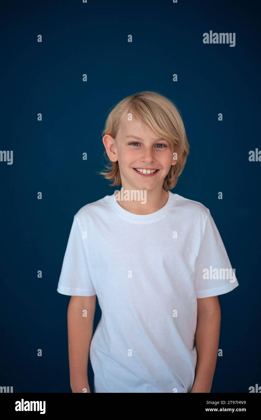 Smiling blond boy standing against blue background Stock Photo - Alamy