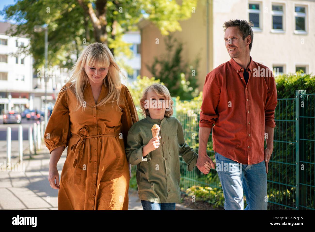 Happy parents walking with son holding ice cream cone at footpath Stock Photo