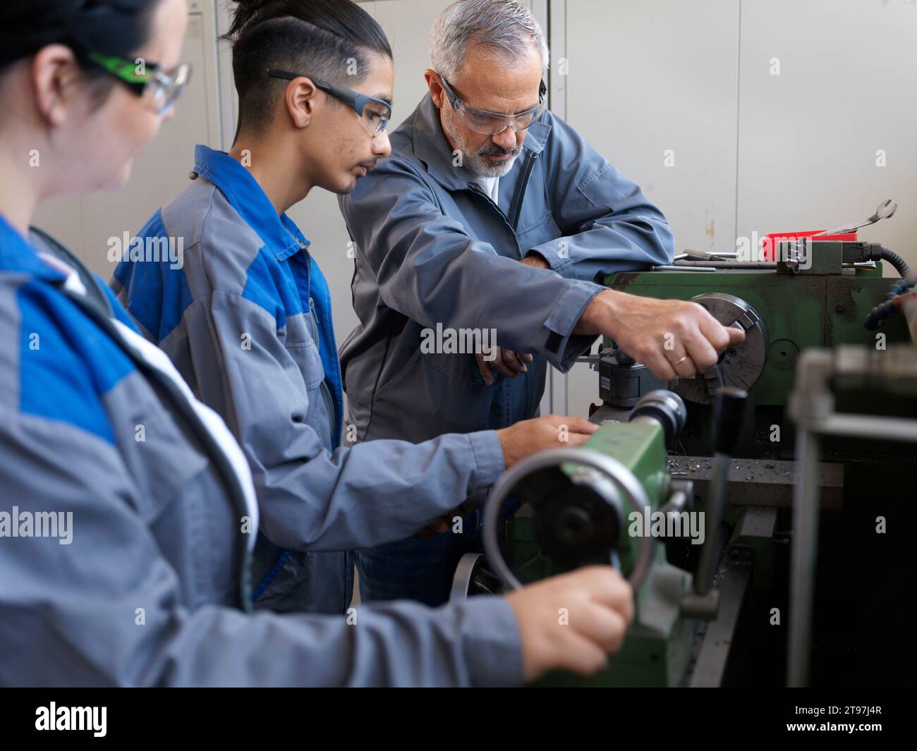Instructor giving lathe machine training to trainees at Stock