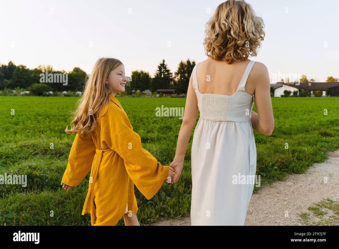 Happy girl holding hands with mother and walking on road Stock Photo ...