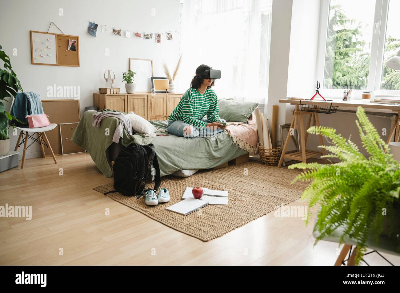 Teenage girl wearing virtual reality simulators playing video game with controller at home Stock Photo