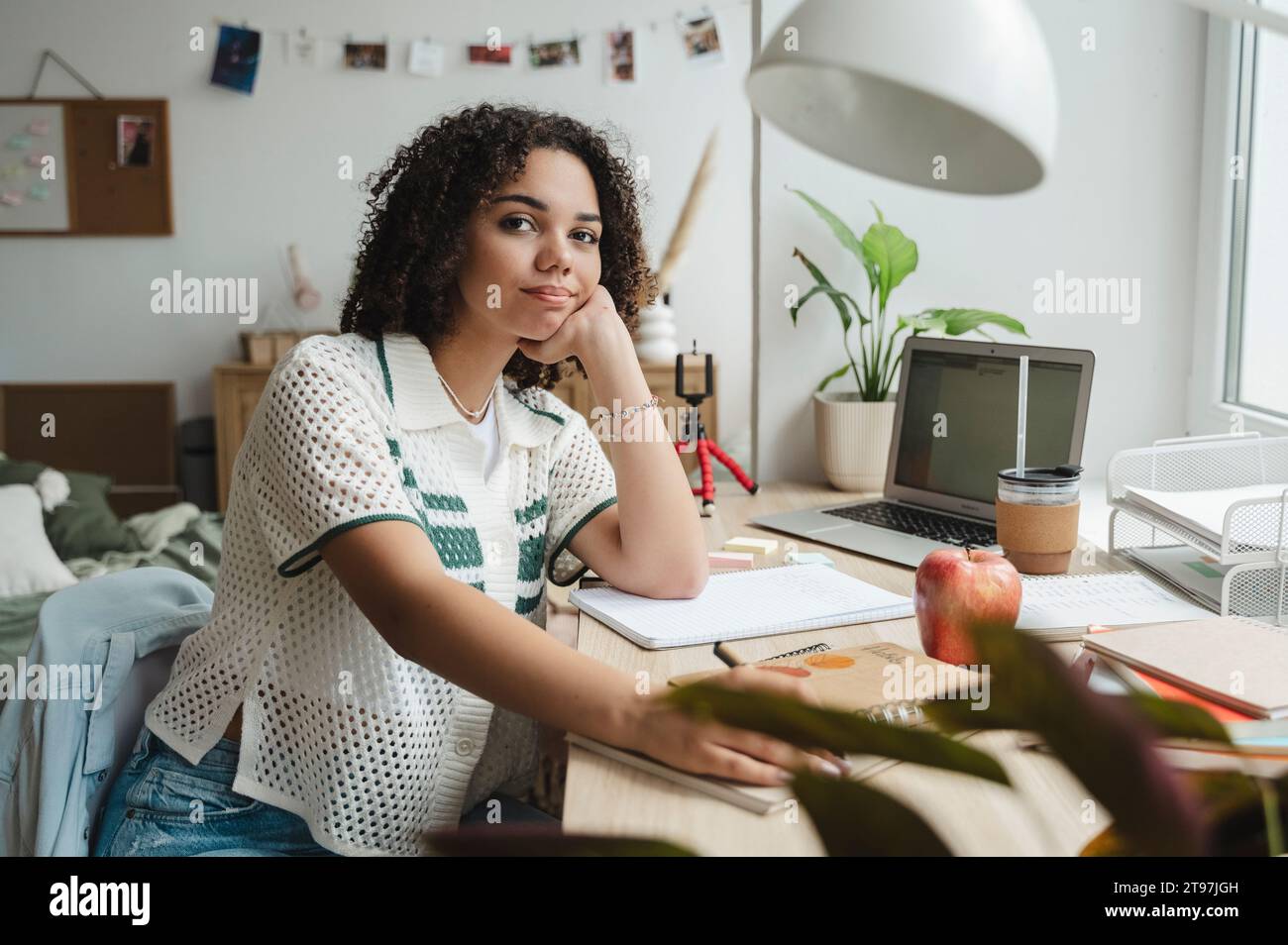 Smiling teenage girl sitting at desk in bedroom Stock Photo - Alamy