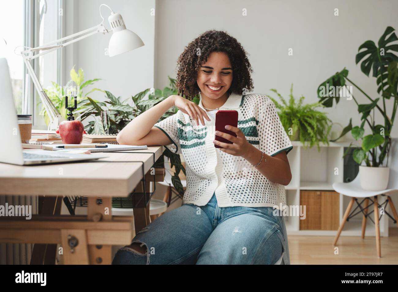 Happy teenage girl using mobile phone at desk Stock Photo - Alamy