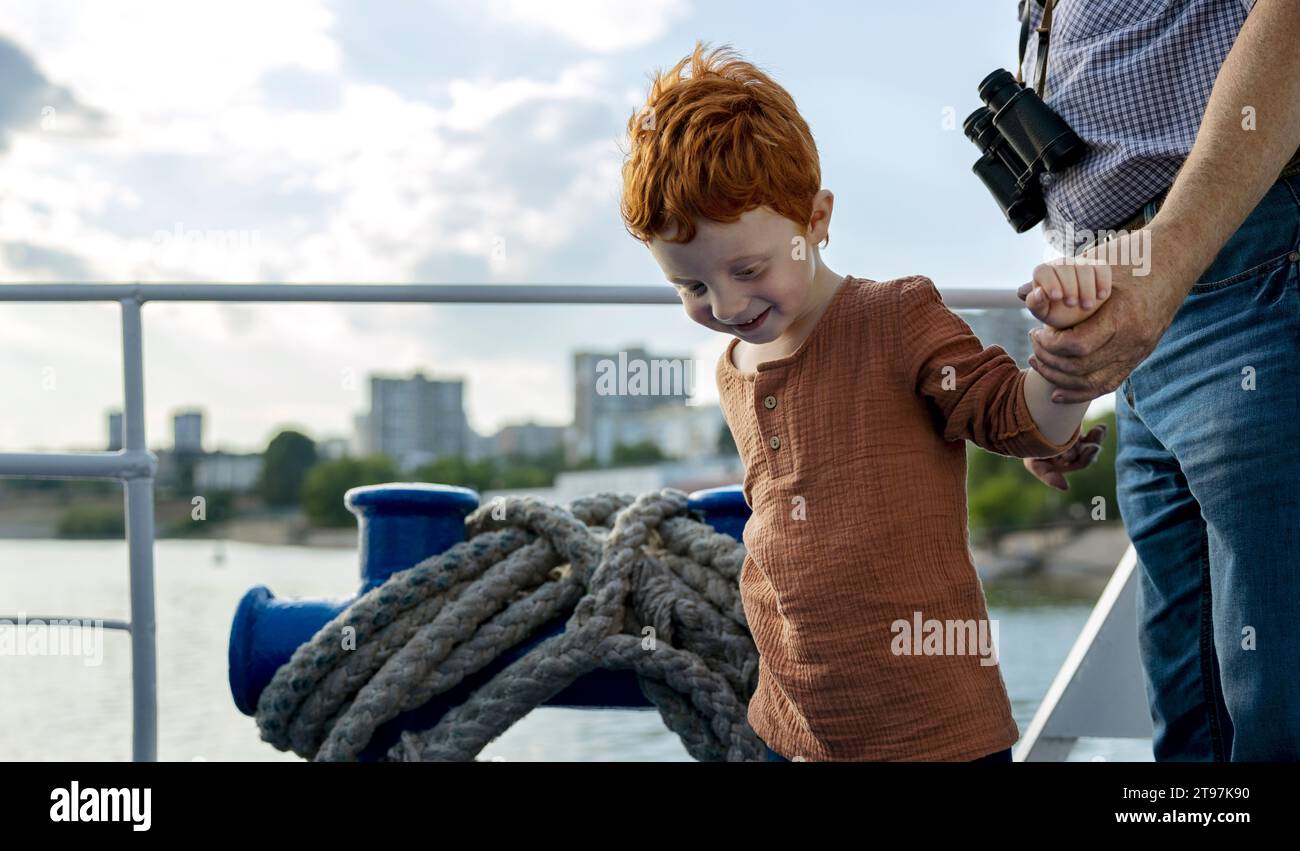 Boy holding hands with grandfather on ship Stock Photo