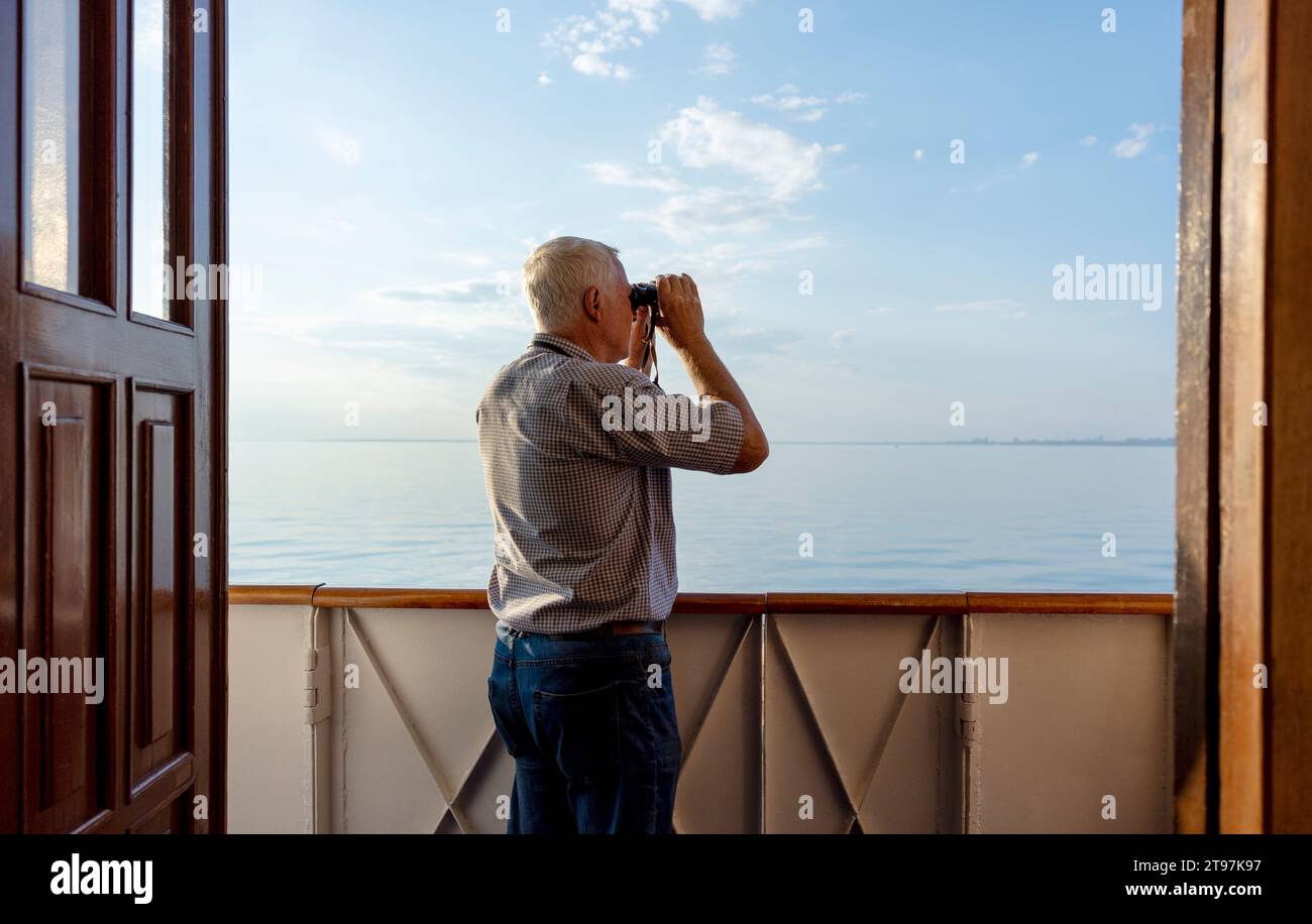 Man looking at sea through binoculars from ship Stock Photo