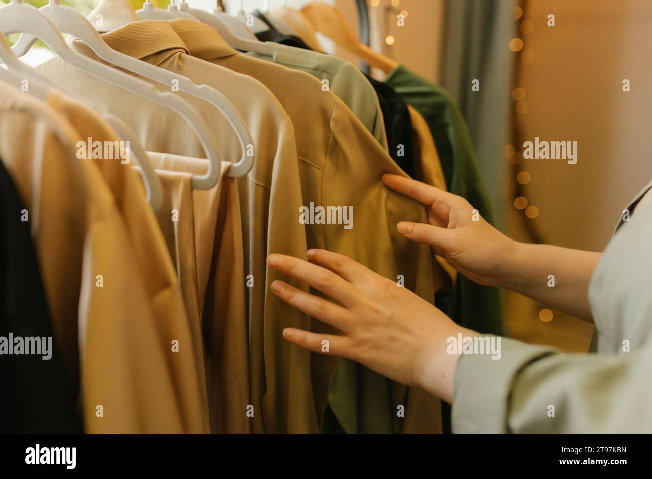 Hands of woman choosing dress from clothes rack in store Stock Photo
