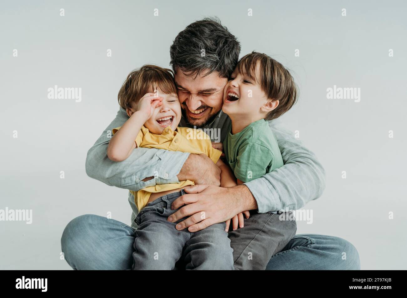 Happy father having fun and hugging children against white background Stock Photo