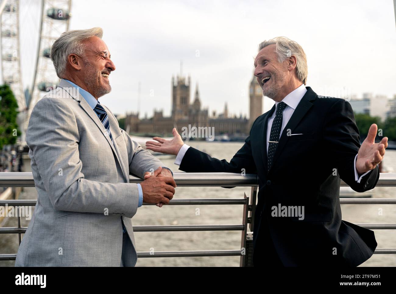 Cheerful senior businessmen talking to each other on bridge near ...