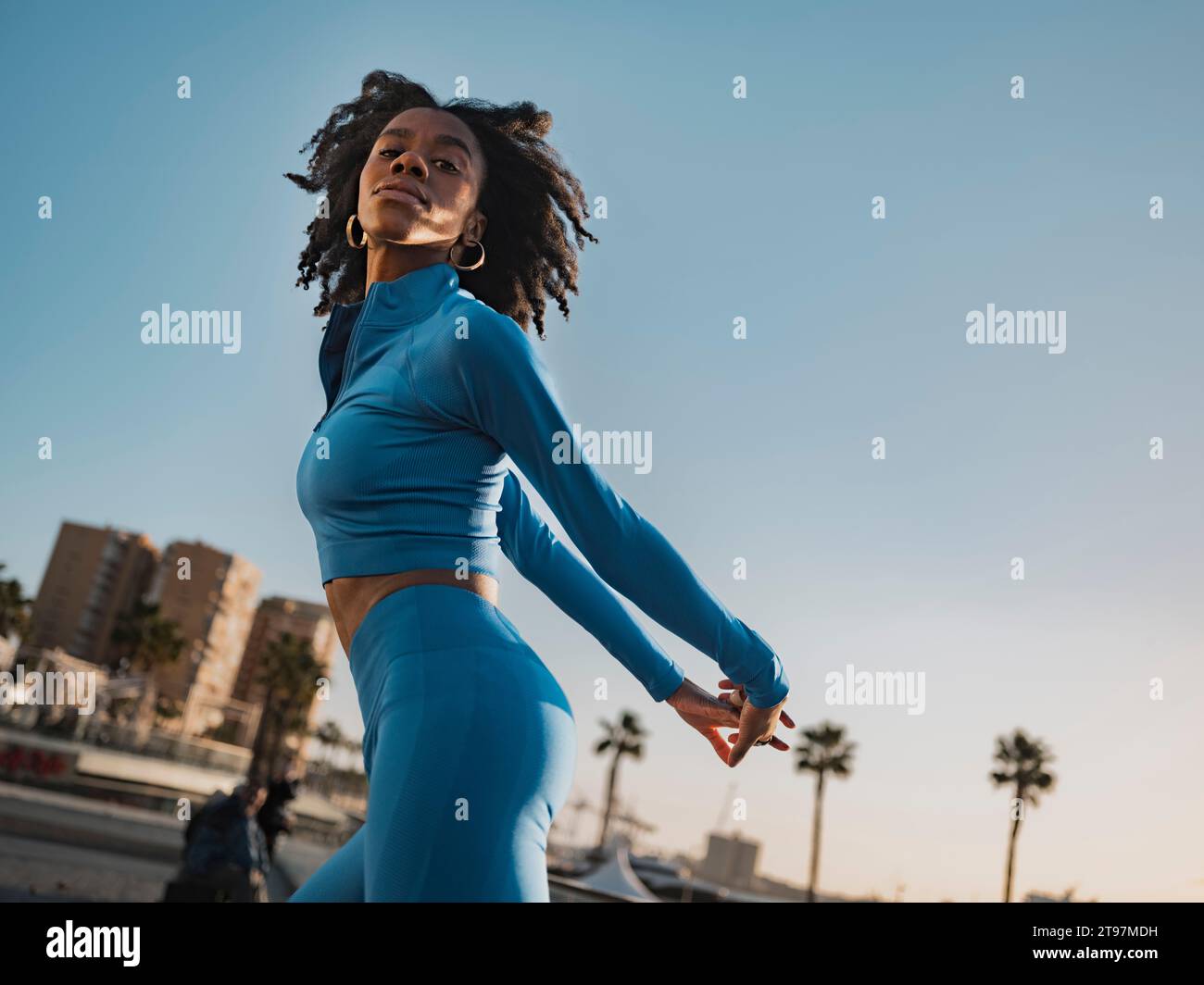 Beautiful woman in sports clothing posing with hands behind back Stock Photo