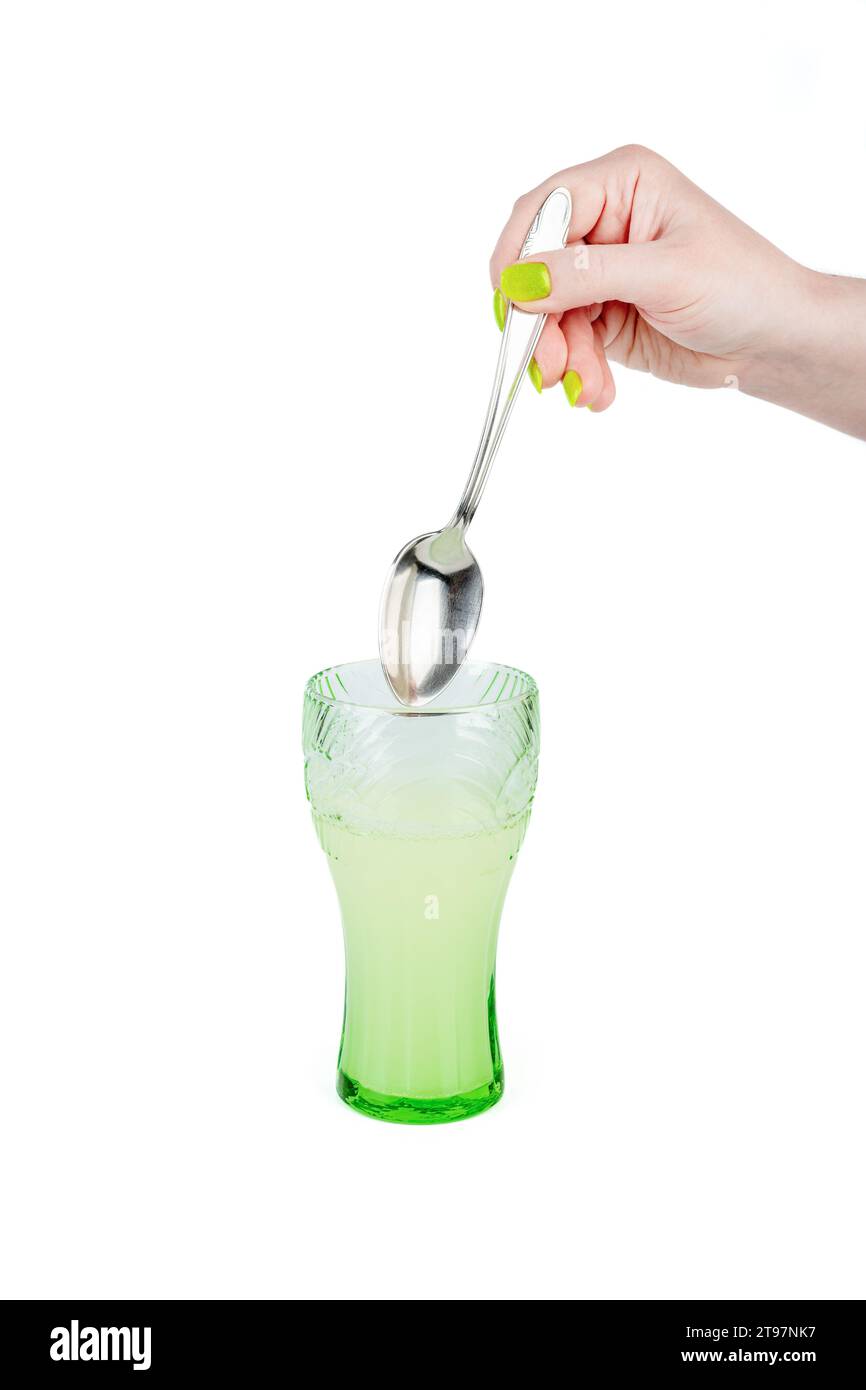 A woman is about to mix powdered medicine or protein in a glass of water. Instant drink with food additive. Stock Photo