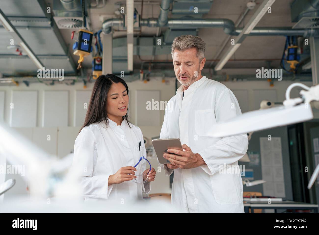 Scientists discussing over tablet PC in laboratory Stock Photo