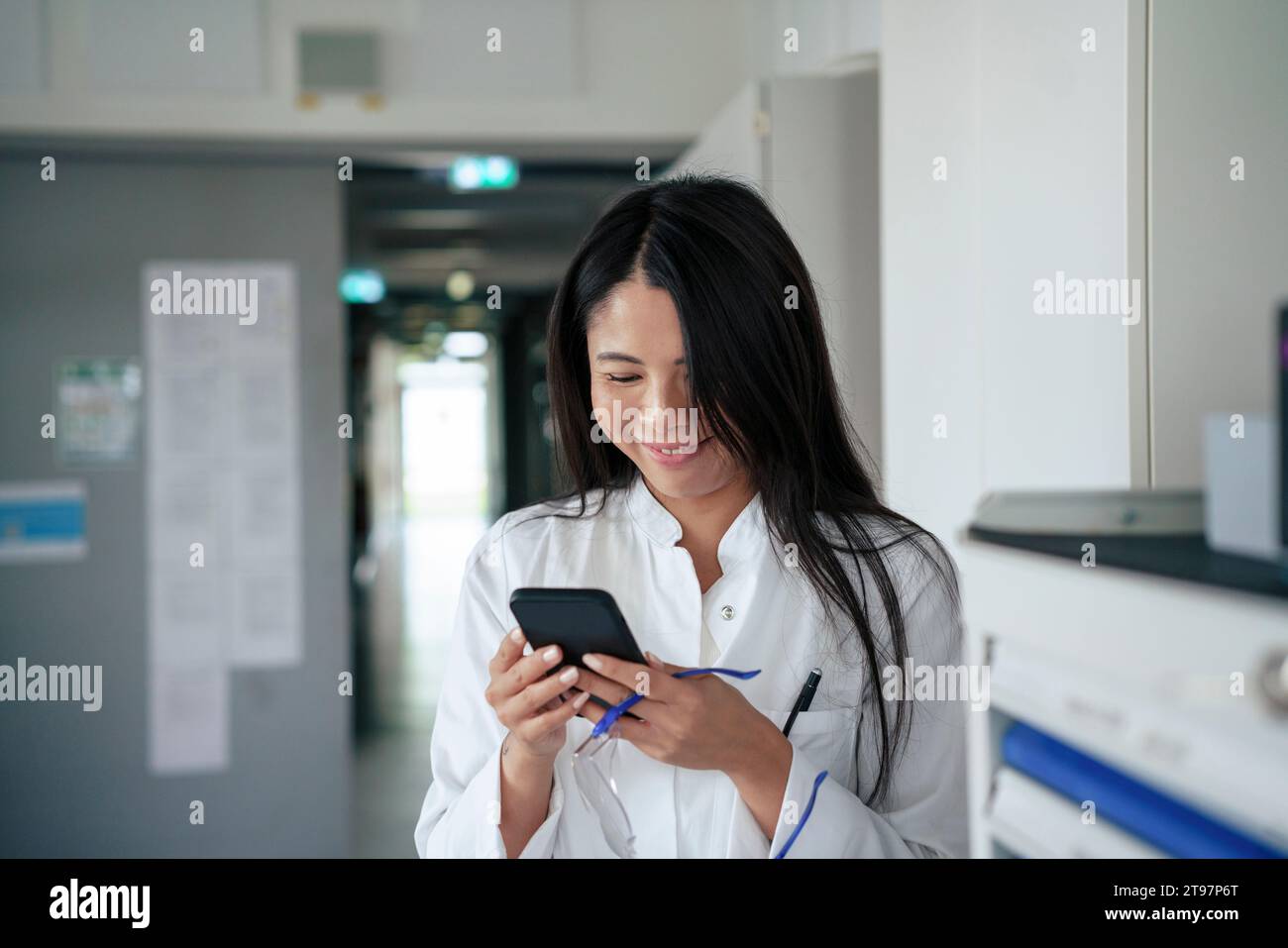Happy scientist using smart phone in laboratory Stock Photo