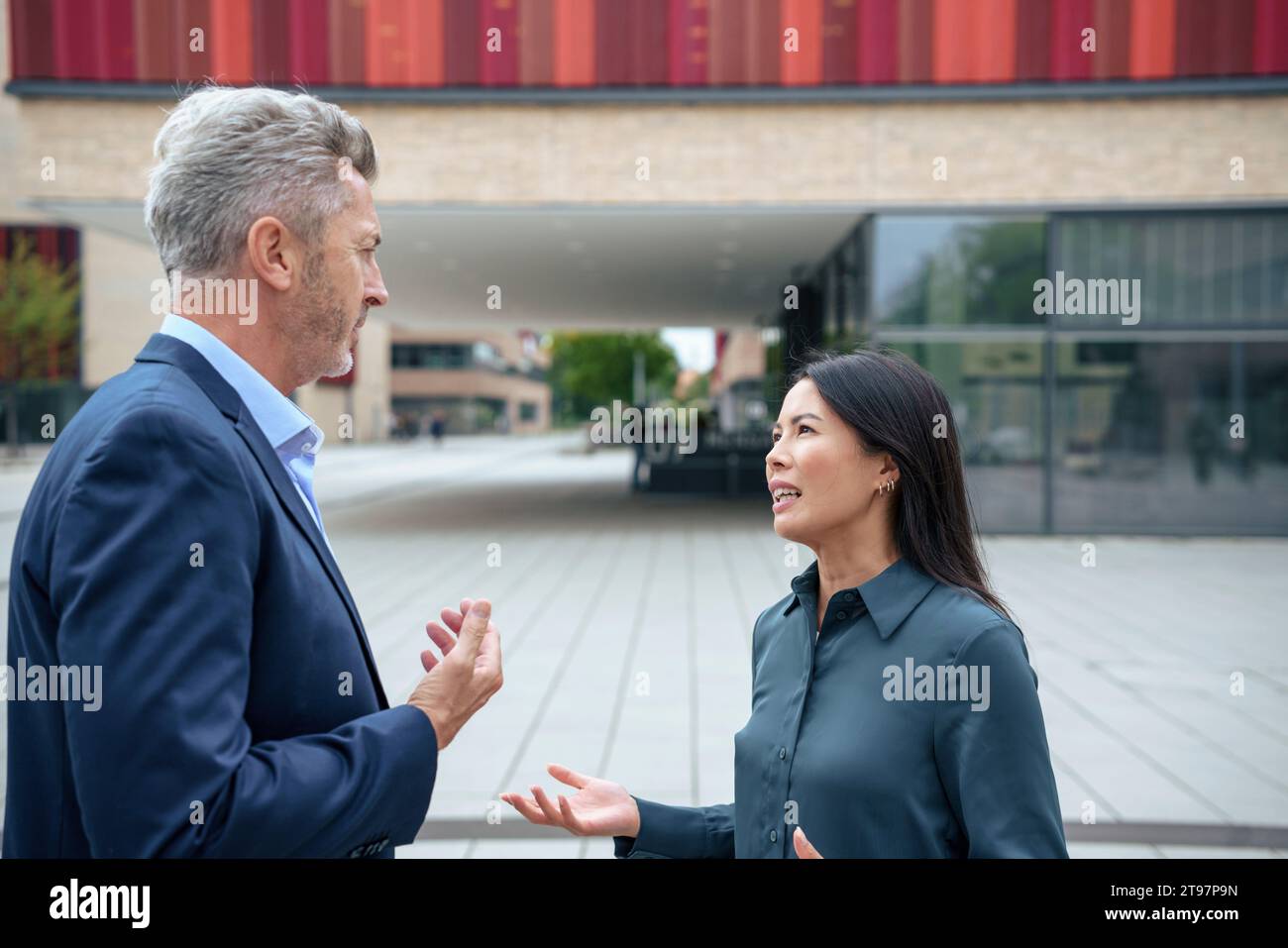 Businesswoman discussing with colleague near office building Stock Photo