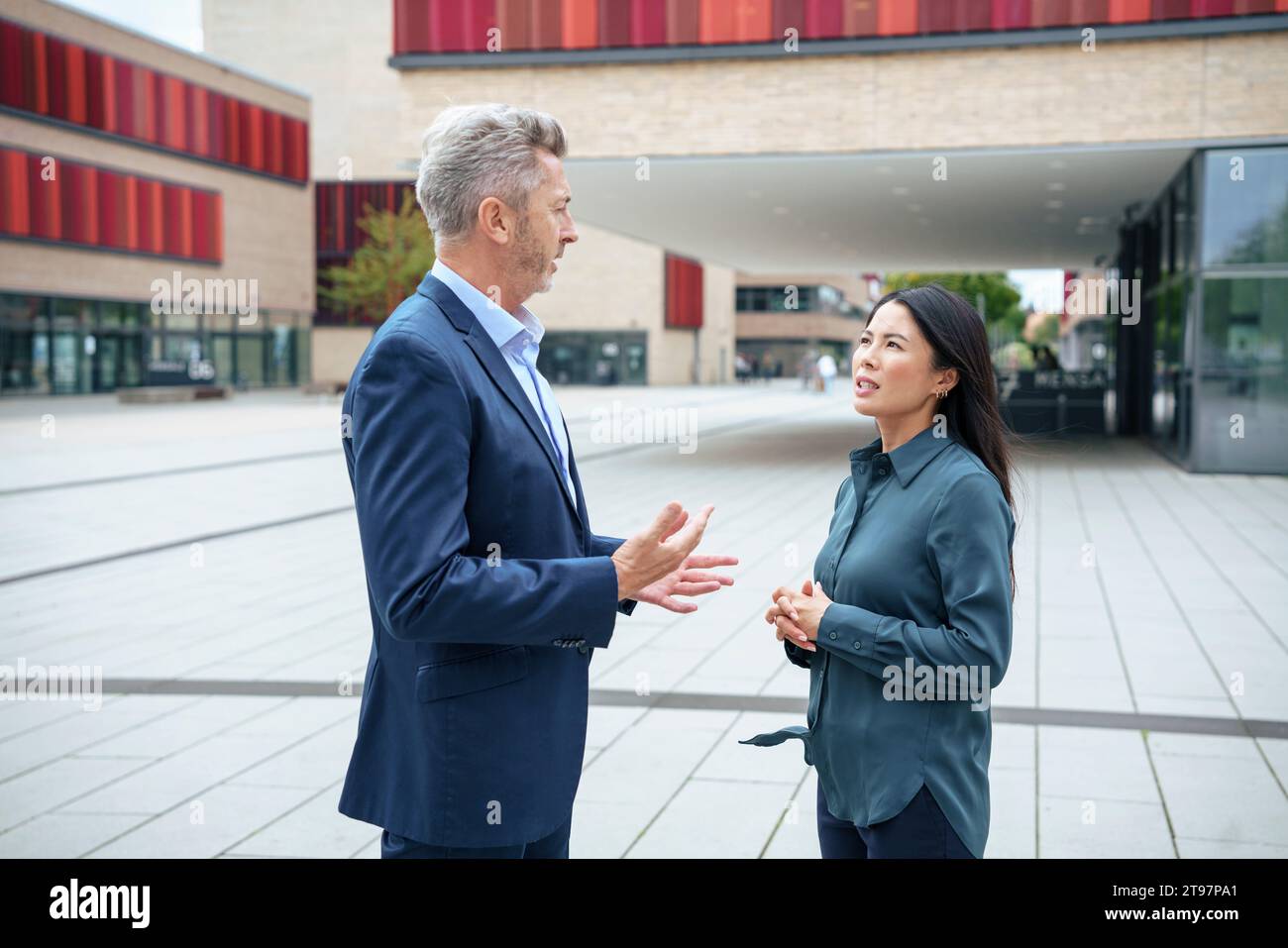 Businessman discussing with businesswoman in office park Stock Photo
