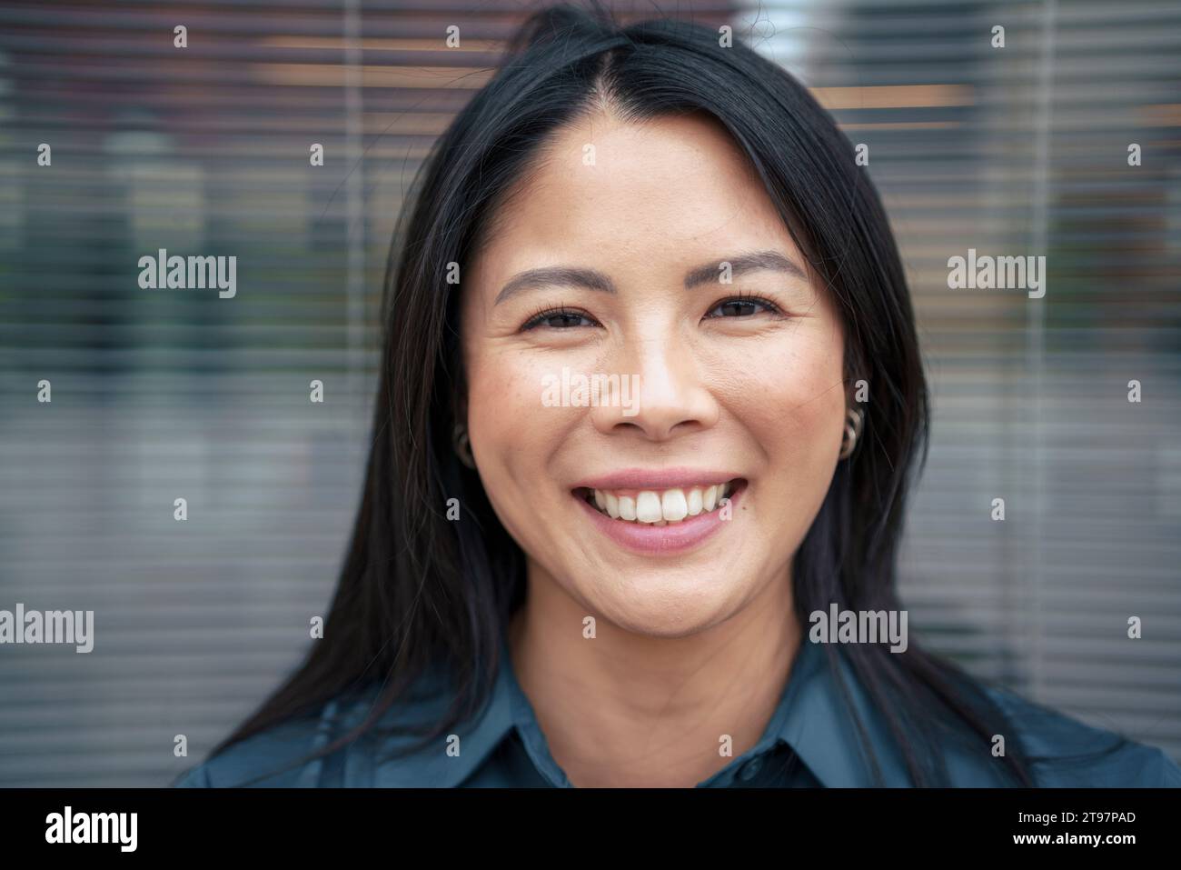 Happy businesswoman with black hair in front of glass Stock Photo