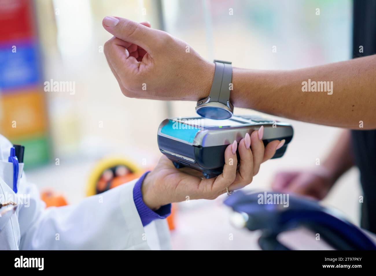 Hand of customer paying via tap to pay method through smart watch at