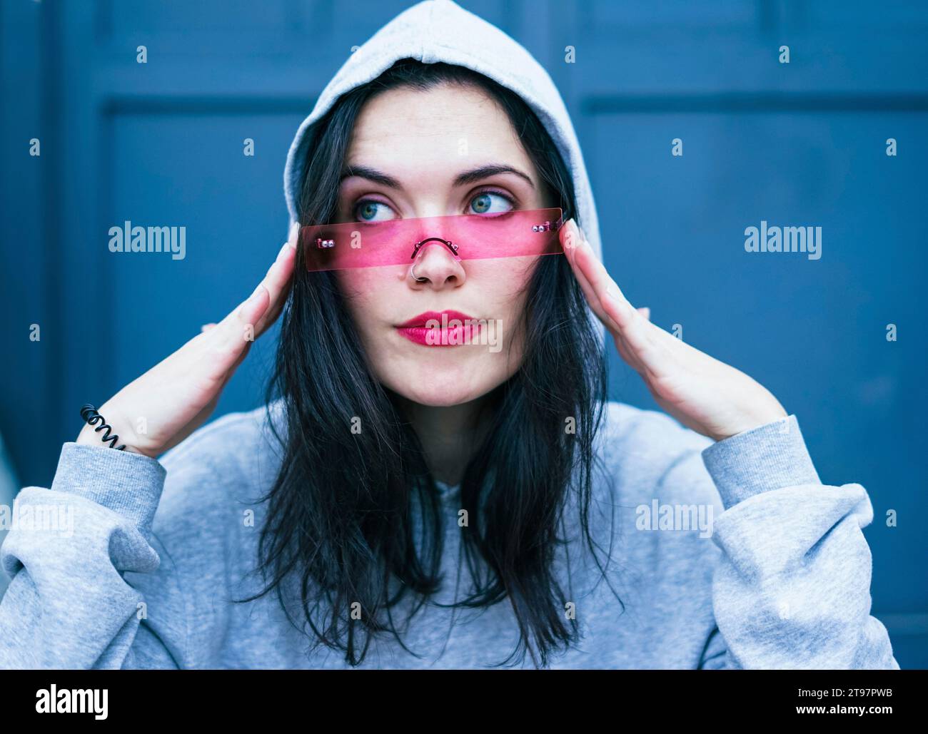 Young woman wearing pink lipstick and adjusting smart glasses Stock Photo