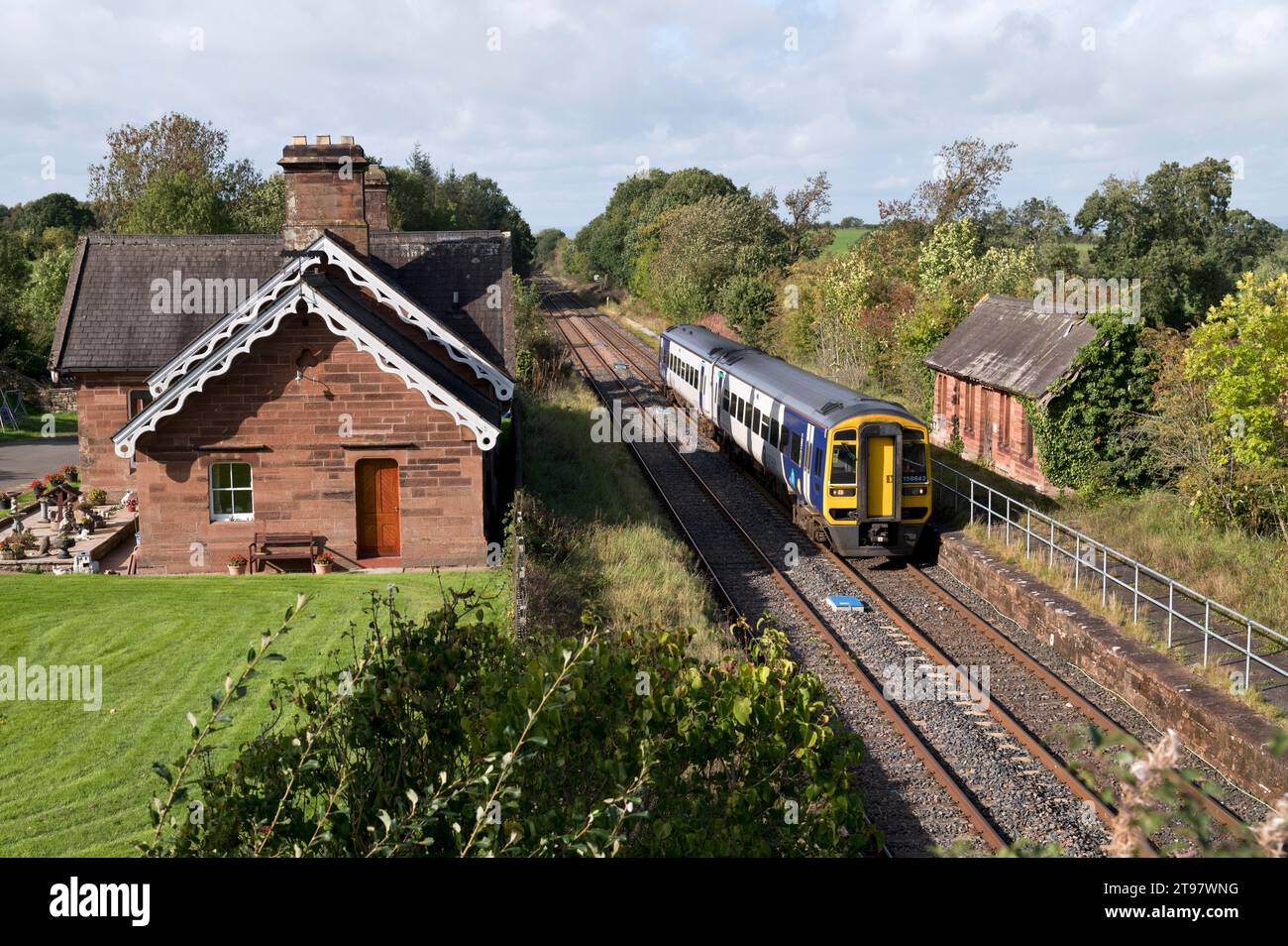 A Sprinter passenger train passes the former station of Cumwhinton, on the Settle-Carlisle railway near Carlisle, Cumbria. Now a private dwelling. Stock Photo