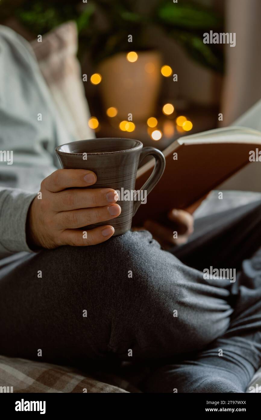 A caucasian man relaxing at home, reading a book, drinking coffee in bed Stock Photo