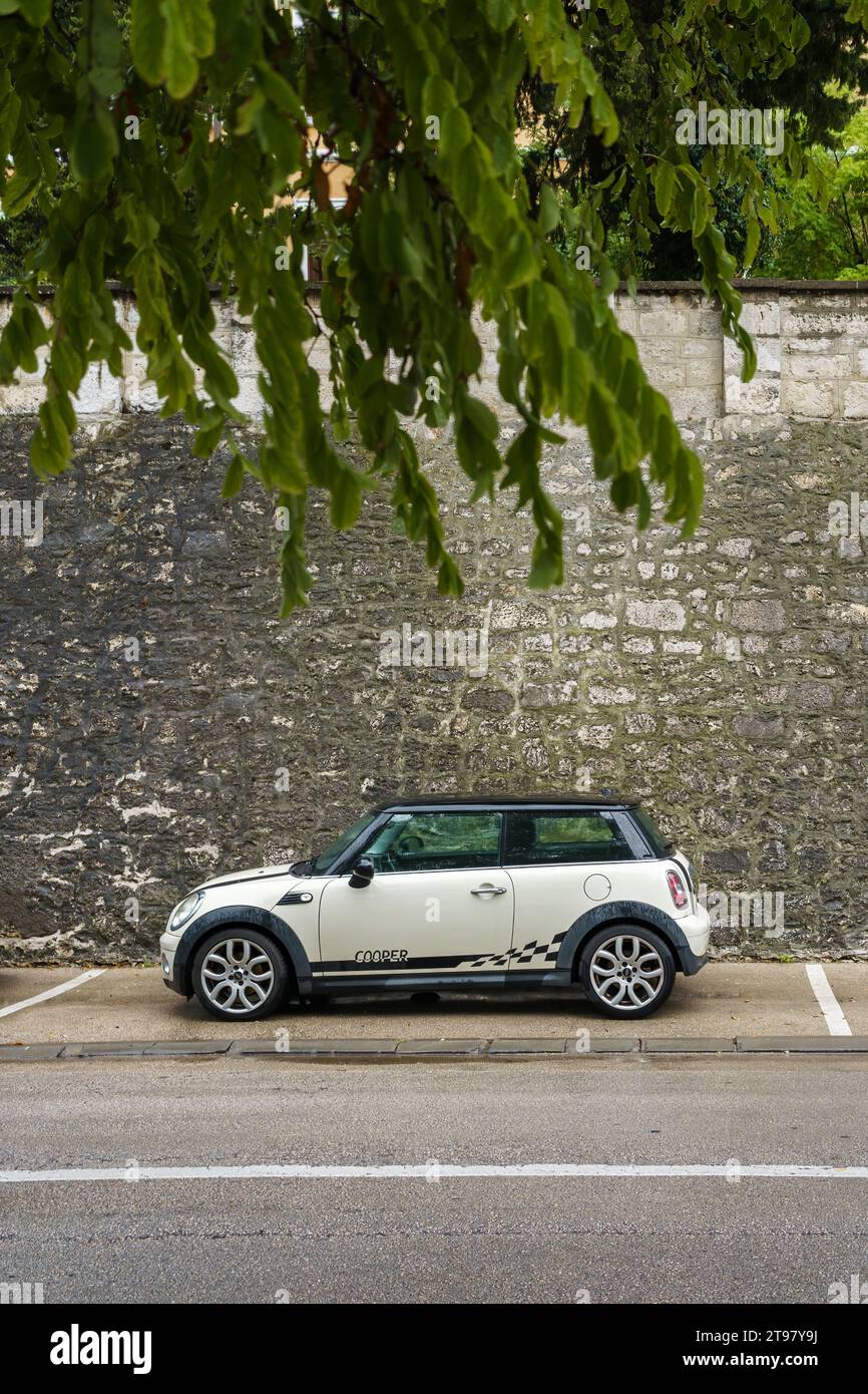 White and black Mini Cooper parked next to an old stone wall in Zadar, Croatia. September 21, 2023. Stock Photo