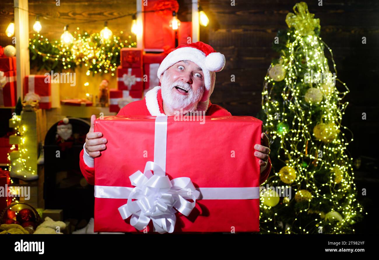 Christmas holiday celebration. Delivery service. Smiling Santa Claus with Christmas gift box. Bearded man in Santa hat with big present. Merry Stock Photo