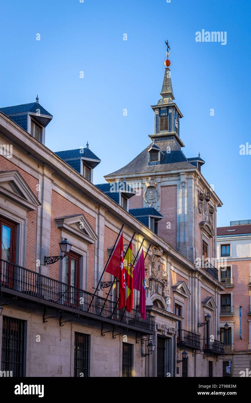 Casa de la Villa in Madrid, Spain, former City Hall building with tower, traditional balconies, brick facade and national flags on Plaza de la Villa. Stock Photo