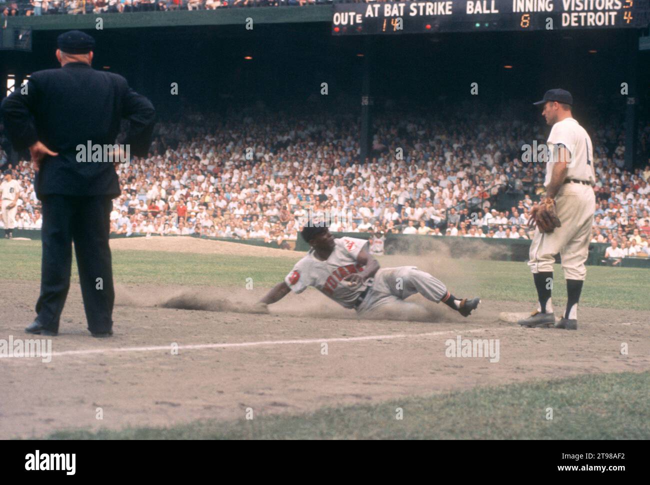 DETROIT, MI - JULY 5: Minnie Minoso #9 of the Cleveland Indians slides into third base as Eddie Yost #1 of the Detroit Tigers and umpire Bill Summers look on during an MLB game on July 5, 1959 at Briggs Stadium in Detroit, Michigan. (Photo by Hy Peskin) *** Local Caption *** Minnie Minoso;Eddie Yost;Bill Summers Stock Photo