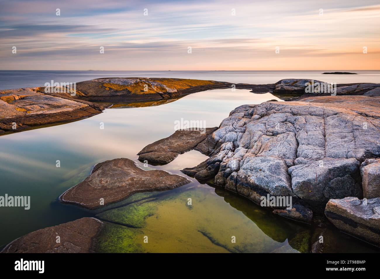 Beautiful sunset over the rocky shore of a beach. Stock Photo