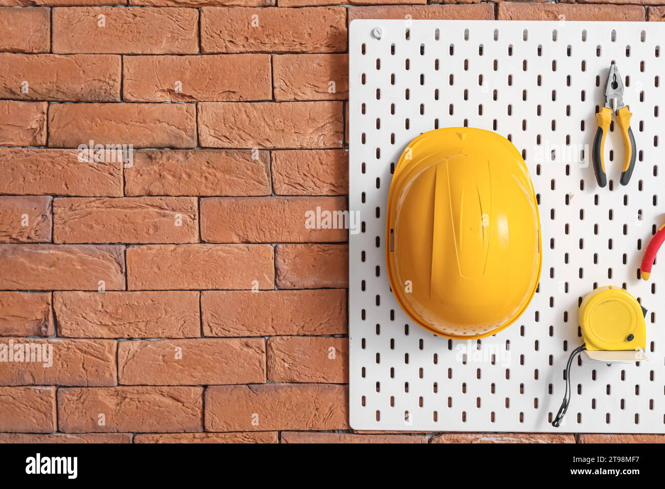 Pegboard with builder's tools on brick wall in workshop Stock Photo