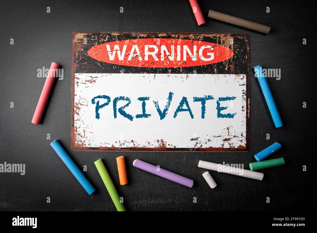 PRIVATE. Metal warning sign and colored pieces of chalk on a dark ...