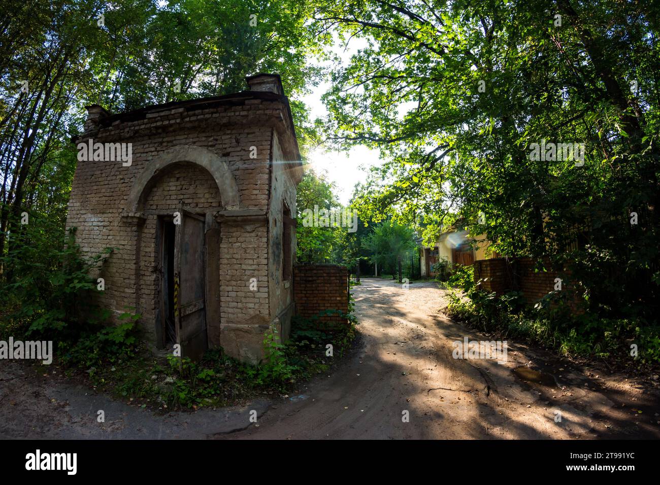 Abandoned checkpoint with a brick security booth surrounded by green ...