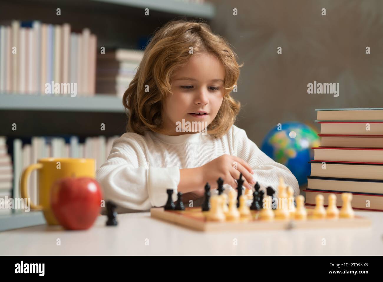 Pupil kid thinking about his next move in a game of chess. Concentrated  little boy sitting at the table and playing chess Stock Photo - Alamy