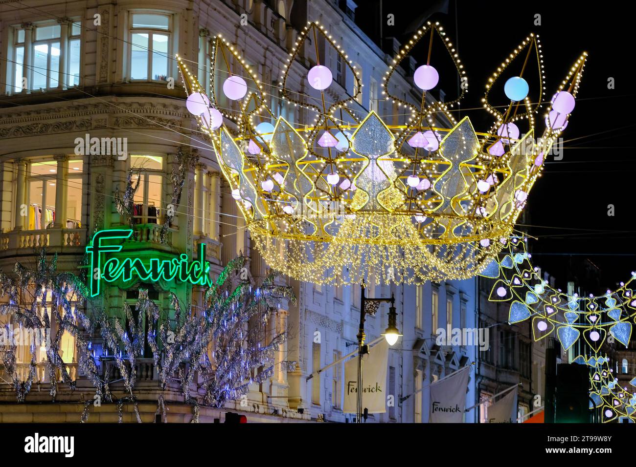 London, UK. 23rd November, 2023. Fenwick department store facade with crown street light decoration. Visitors and shoppers admire the Christmas shop displays in New Bond Street and Old Bond Street, which also features festive lights inspired by the Crown Jewels. Credit: Eleventh Hour Photography/Alamy Live News Stock Photo